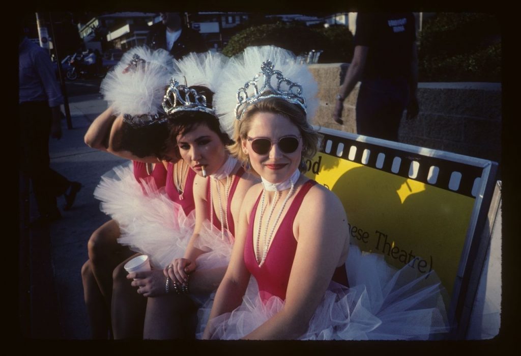 three women in red dresses and crowns sitting on a bench 